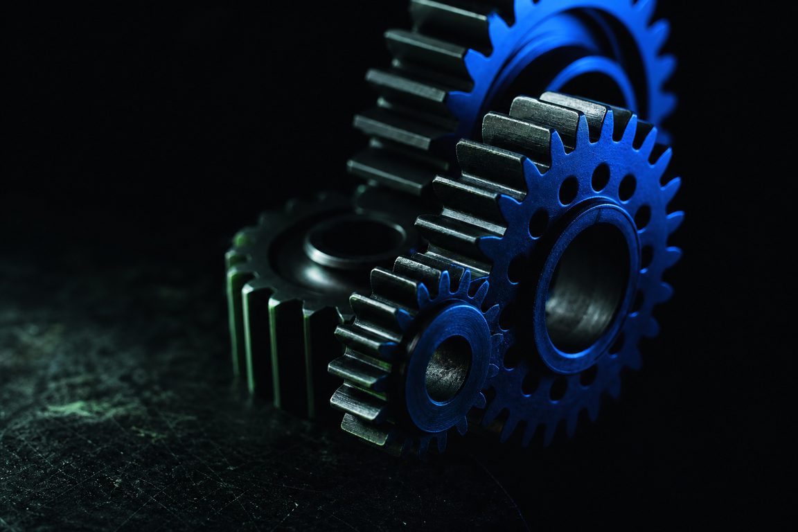 Interlocking machined gears of different sizes on a dark surface