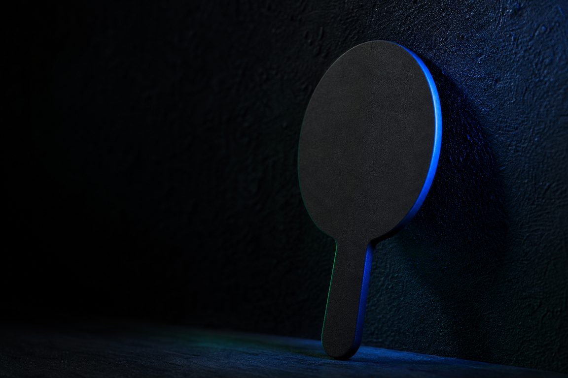 A blank auction-style paddle resting against a dark wall