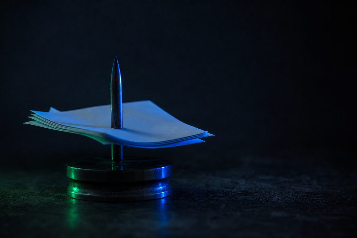 A mechanical order spike holding blank paper slips on a dark counter