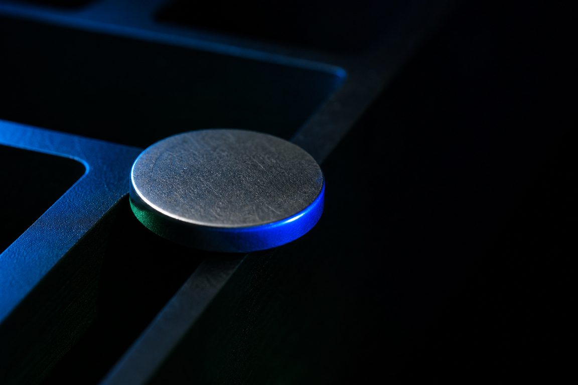 An unmarked nickel token blank on the edge of a machined tray