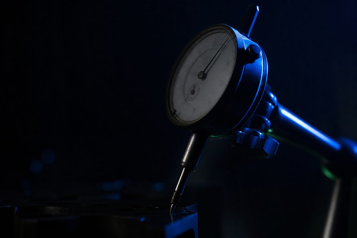 A machinist dial indicator with an unreadable face, needle mid-sweep
